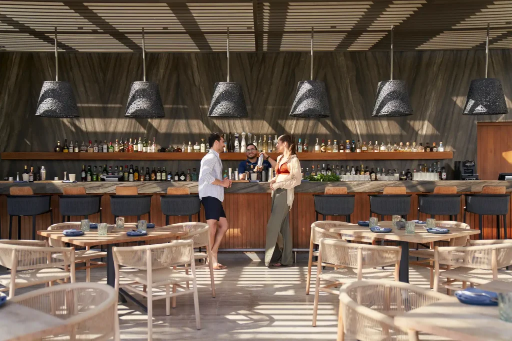 Couple enjoying delicious cocktails on the terrace of the resort's pool bar, overlooking a stunning view in a relaxed atmosphere.