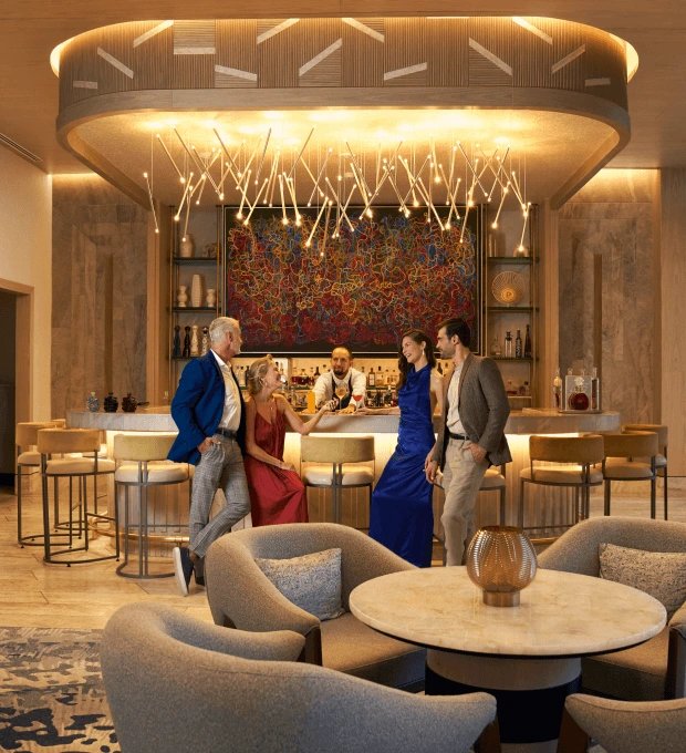 An elegant group of friends enjoying their sophisticated drinks at the Peacock Alley bar in Waldorf Astoria Cancun, exuding a refined and stylish atmosphere.