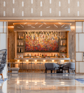 A front view of the Peacock Alley bar with a large painting behind it, featuring warm ambient lighting that enhances its elegant and sophisticated atmosphere.