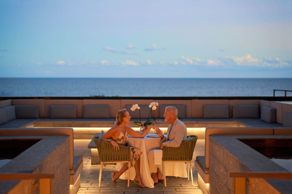 A couple enjoying a nighttime evening in the upper area with stunning ocean views, creating a romantic and serene atmosphere.