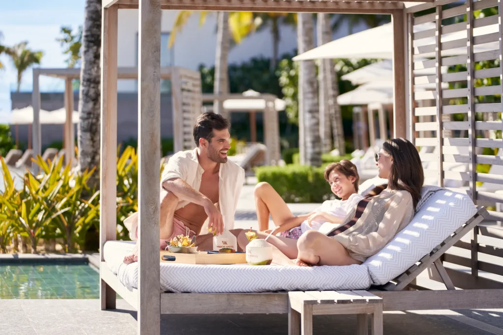 Family enjoying a relaxing moment by the pool, surrounded by a luxurious and scenic resort setting.