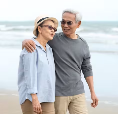 Older Japanese couple walking hand in hand along the beach