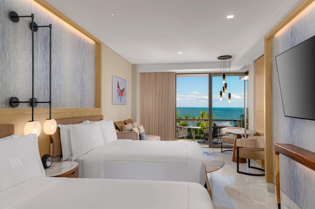 Bright suite with two beds, private balcony, and ocean view