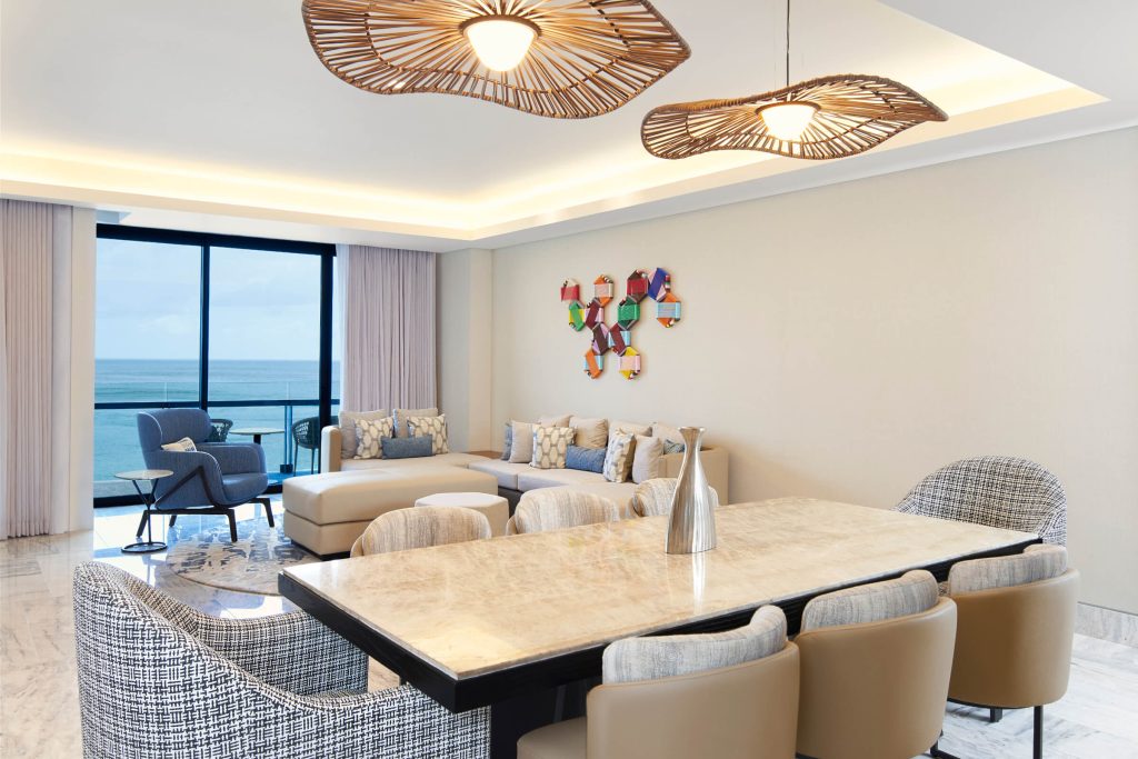 Spacious suite with elegant living area, marble dining table, and ocean view.
