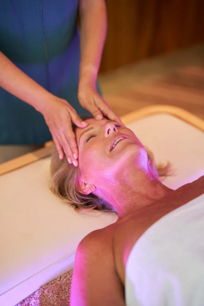 A woman enjoying a relaxing head massage at Waldorf Astoria Spa, surrounded by a serene and tranquil atmosphere.