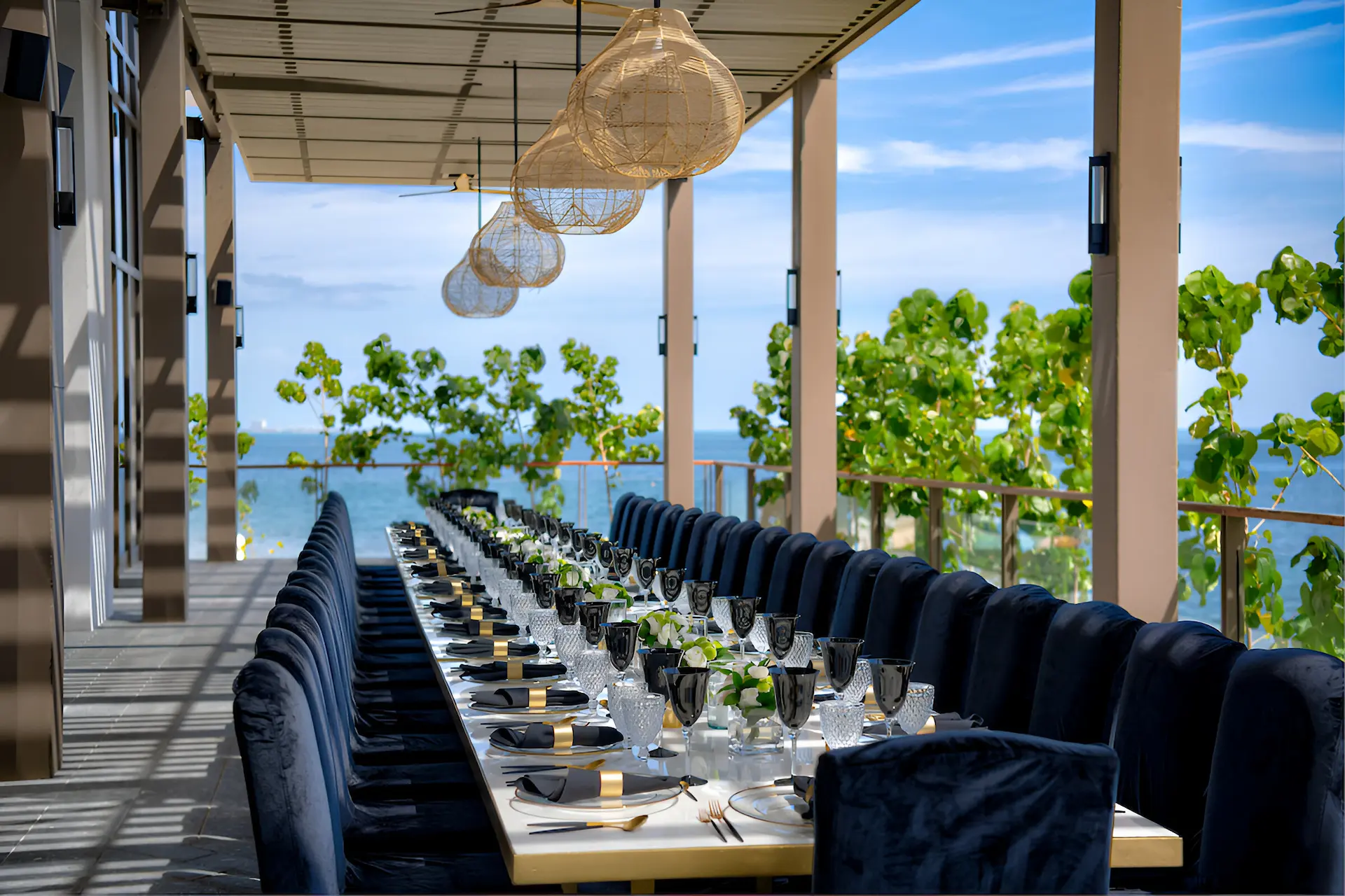 Elegantly set long table on the terrace of Waldorf Astoria Cancún, ready for a celebration with ocean views