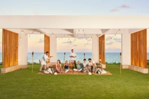 Group enjoying an elegant outdoor dining experience at Waldorf Astoria Cancun, with ocean views, soft lighting, and personalized service.