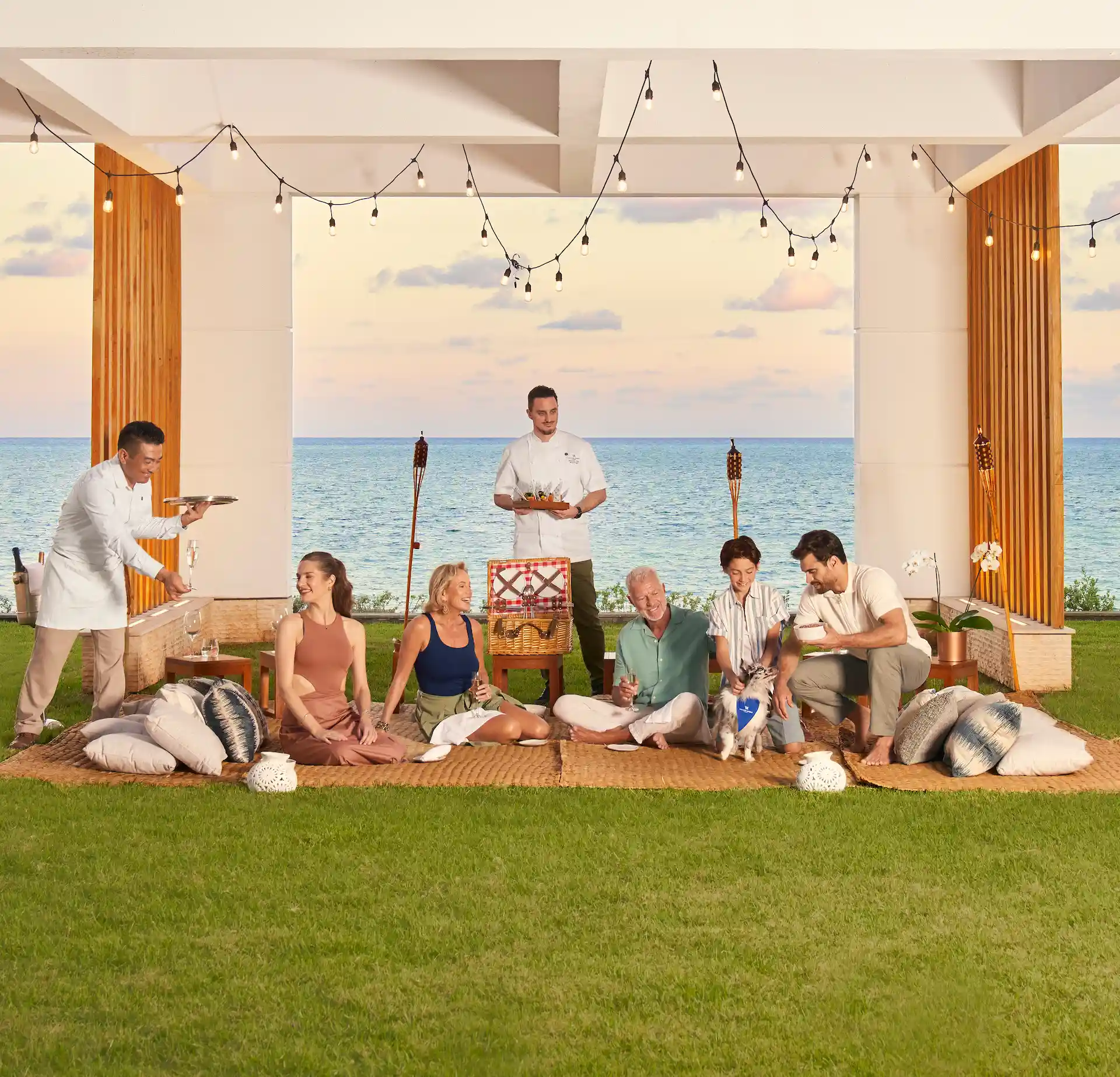 Group enjoying an elegant outdoor dining experience at Waldorf Astoria Cancun, with ocean views, soft lighting, and personalized service.