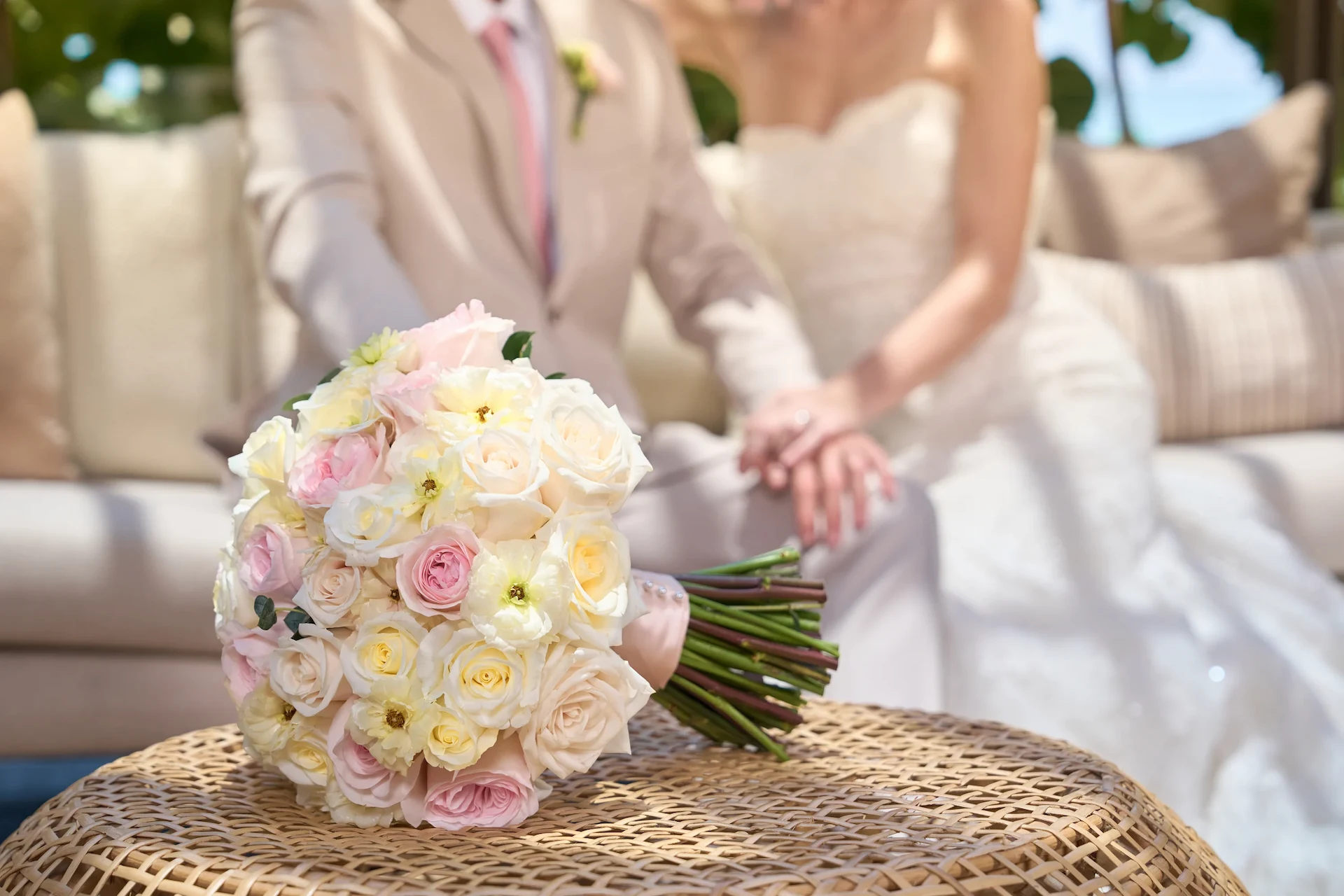 Bridal bouquet with newlywed couple in the background on their wedding day at Waldorf Astoria Cancún