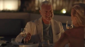 A couple enjoying a romantic dinner, gazing at each other with smiles as they share an intimate moment over a beautifully set table with candlelight.