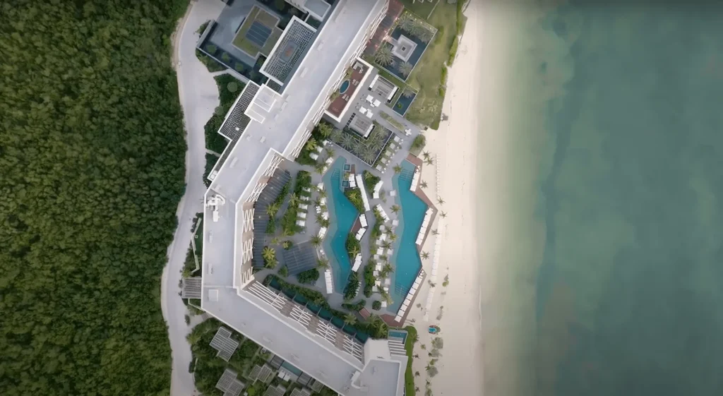 Aerial view of the Waldorf Astoria Cancún, showcasing its elegant architecture by the turquoise sea, surrounded by lush greenery and infinity pools.