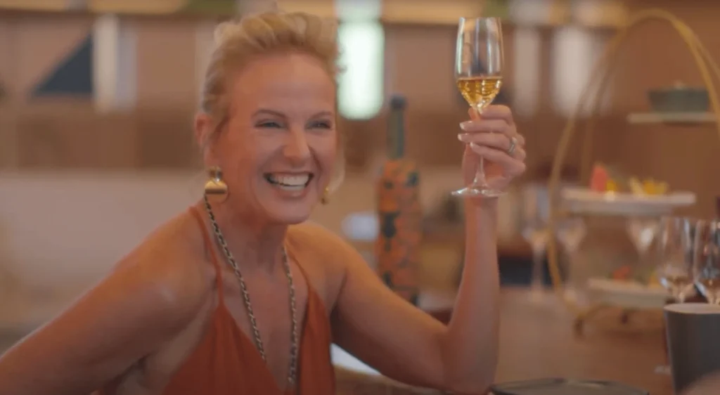 A joyful woman holding a glass of champagne, smiling radiantly as she enjoys a moment of celebration and elegance.